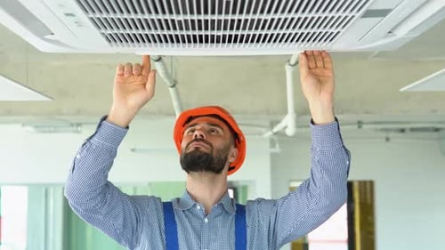 Adult Working on White Air Conditioning Unit on Ceiling