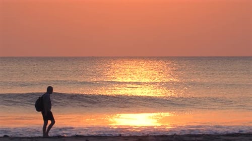 Silhouette of Adult Walking on Beach at Sunrise