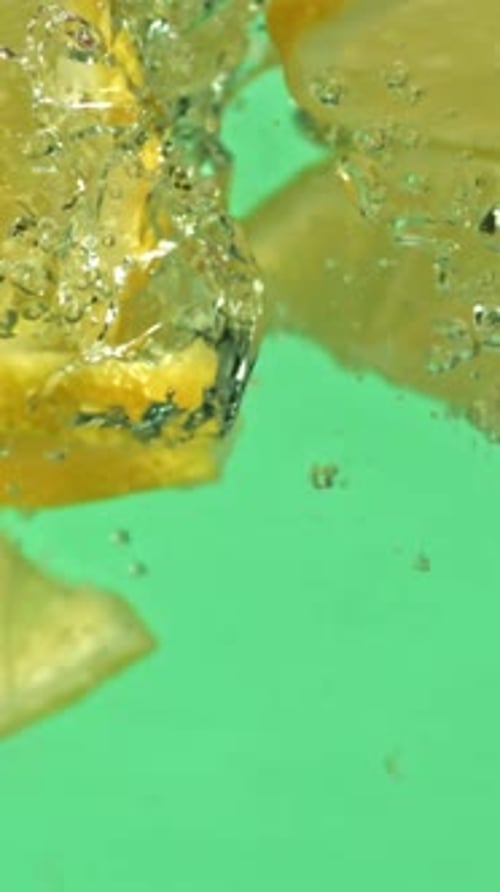 Lemon Slices Falling Under Water on a Green Background Filmed on a Highspeed Camera at 1000 Fps