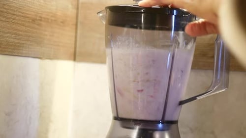 Person Making Smoothie in Blender with Food and Liquid in Kitchen Appliance