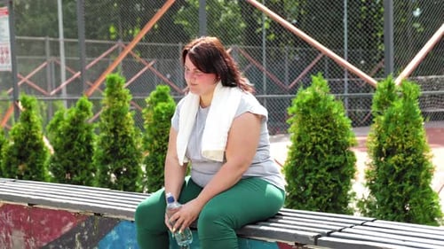 Woman Resting on Bench After Exercising Outdoors