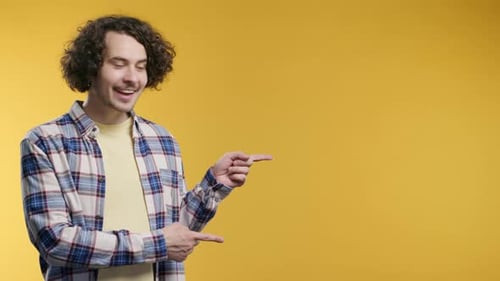 Man Pointing to Copy Space on Yellow Background