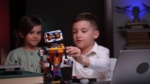 Der Junge mit einem kleinen Mädchen schließt den Bau des Roboters ab