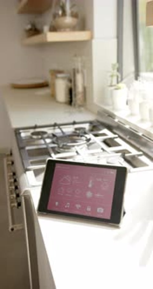 Vertical video: Tablet displaying smart home controls on kitchen counter near stove