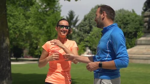 Sportive Couple Resting and Drinking Water in City Park Active