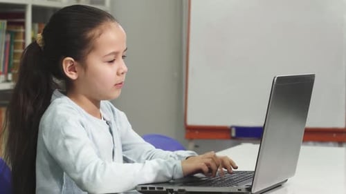 Fröhliches asiatisches Mädchen, das mit ihrem Laptop online lernt