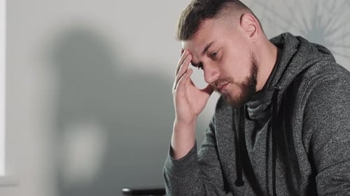 Pensive Man in Studio with Headache Young Adult Male Holding His Head Showing Signs of Stress or
