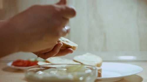 Hands Spreading White Sauce on Slice of Bread