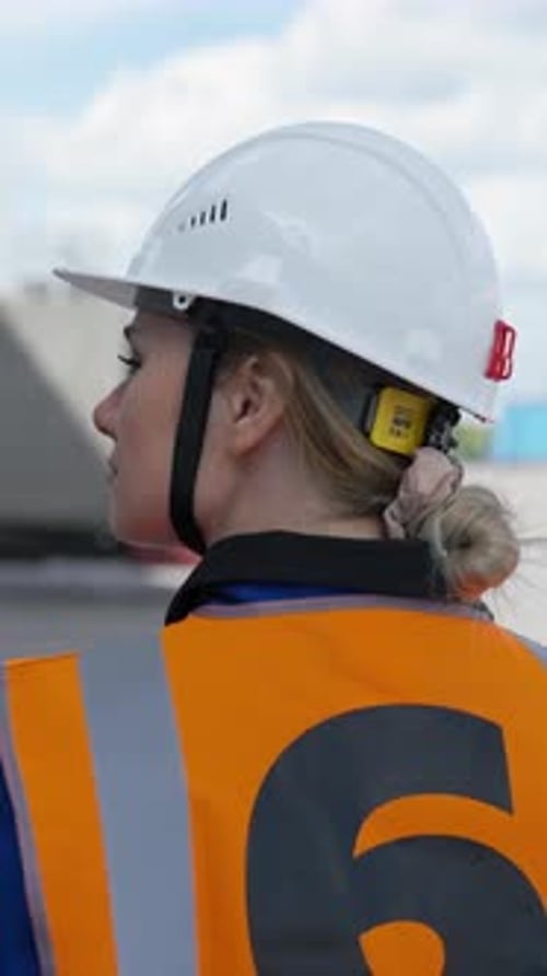 Vertical of Female Engineer Walks Near Storage Terminal Looking Around