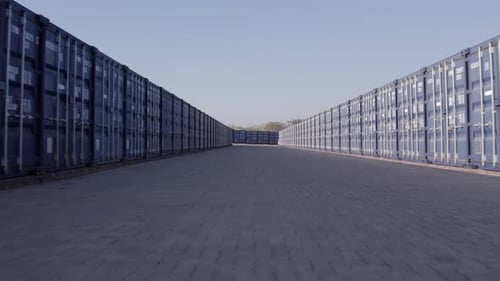 Niedrige Luft überfliegt den Boden zwischen Schiffscontainern, bevor sie aufsteigt