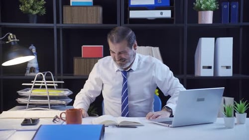 Businessman having a nervous breakdown in his office at night.