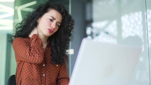 Woman Massaging Stiff Neck While at Computer
