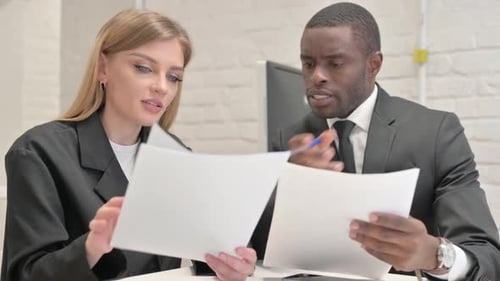 Businesswoman and African Businessman Discussing Business Report in Office