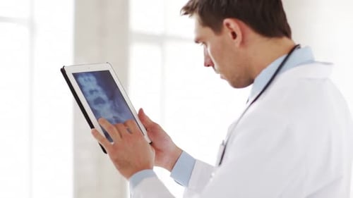 Professional doctor analyzing x ray scan on tablet pc in modern clinic