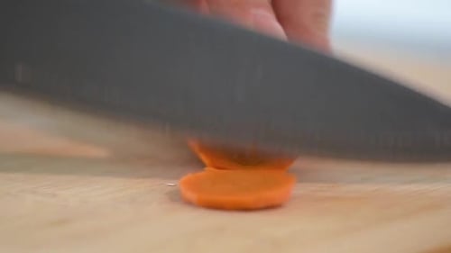 Extreme close-up of Woman's hand cutting a carrot.Side frame.