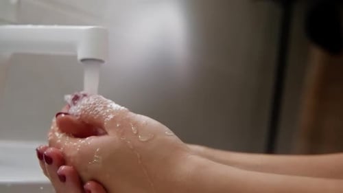 Woman Washing Hands Under Faucet