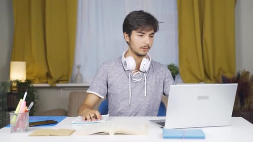 Young Man Studying with Laptop and Book Indoors