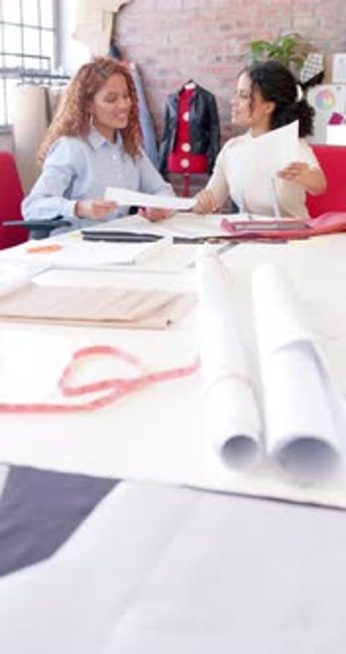 Fröhliche, vielfältige Modedesignerinnen diskutieren im Studio über Stoffe, Zeitlupe, vertikal