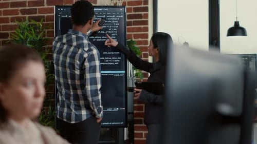 Systemingenieur analysiert Code auf einem großen Bürodisplay