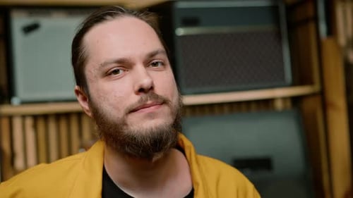 Porträt eines jungen lächelnden bärtigen Rockkünstlers mit E-Gitarre im Aufnahmestudio aus nächster Nähe