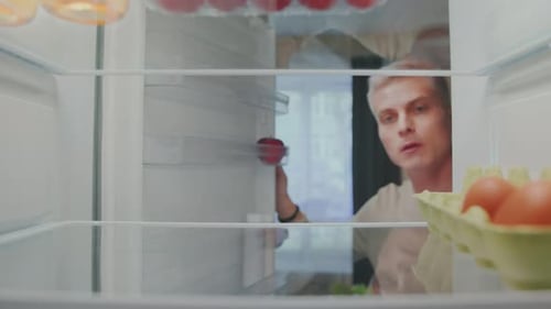 Person Opens Empty Refrigerator Door With One Apple