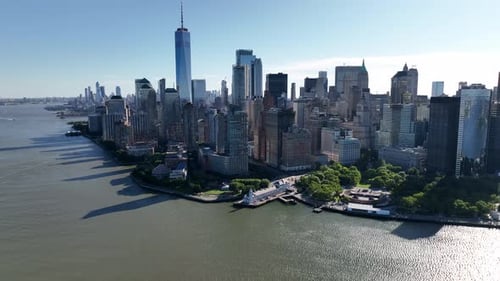 An aerial view of lower Manhattan and New York Harbor on a sunny day with blue skies. The drone came