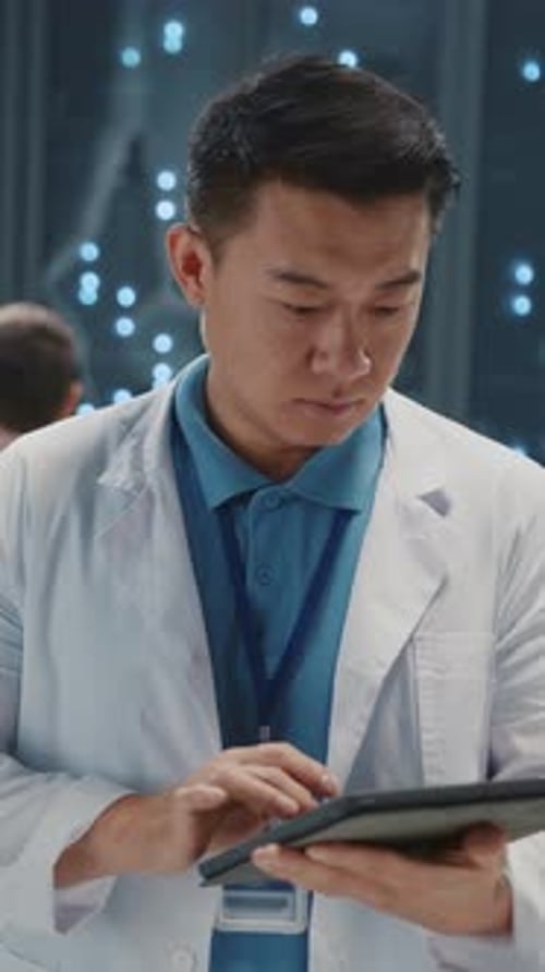 Porträt eines asiatischen chinesischen IT-Entwicklers im weißen Laborkittel mit Tablet-Computer