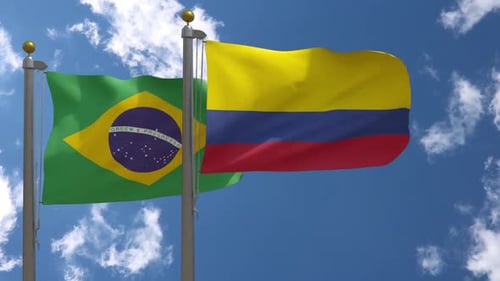 Flags of Brazil and Colombia Waving Against Blue Sky