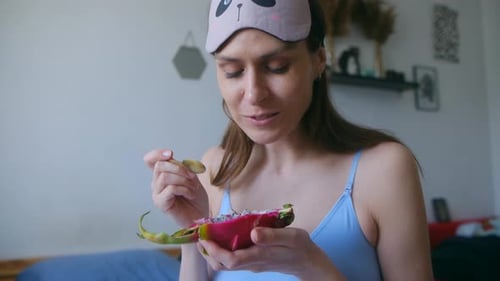 Woman Eating Dragon Fruit for Breakfast in Bed