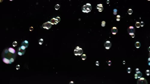Overlay of soap bubbles flying on black background. Slow motion