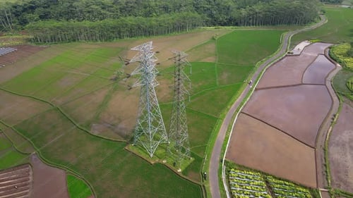 Aerial drone shot over high voltage electricity tower in the middle of rice field - Indonesia, Asia