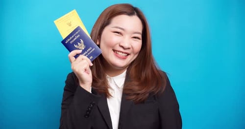 Woman Holds Passports in Front of Blue Backdrop