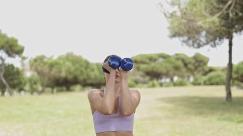 Woman Doing Bicep Curls with Dumbbells in Park