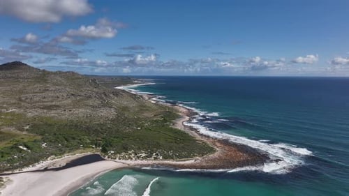 Drone crane motion reveal azure blue waves washing up on empty Scarborough beach