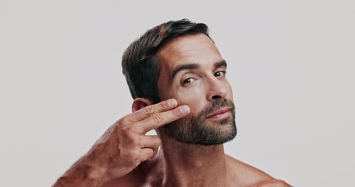 Skincare, hand and face of man in studio checking for pimples, acne or blackheads