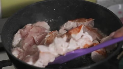 Pieces of Chicken Meat are Fried in a Frying Pan in Home Kitchen