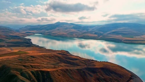 Vistas aéreas del lago, colinas áridas y montañas bajo nubes dramáticas