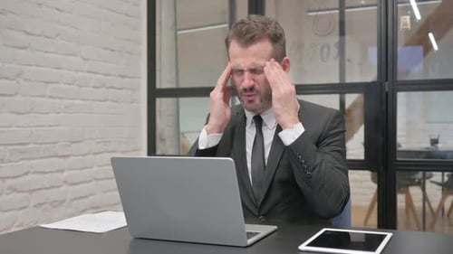 Businessman Working on Laptop, Rubbing Temples