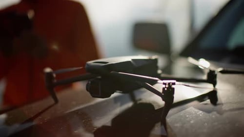 Drone com hélices abertas apoiado no capô de um veículo Drone com hélices estendidas no veículo