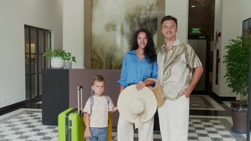 Portrait of Caucasian Family of Three Standing at Hotel Lobby with Suitcase