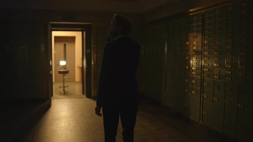Man in Suit Exploring Dark Bank Vault