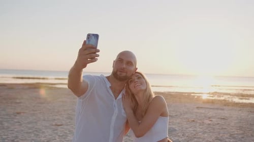 Lovely Couple Standing on the Beach While Making Selfie on the Phone