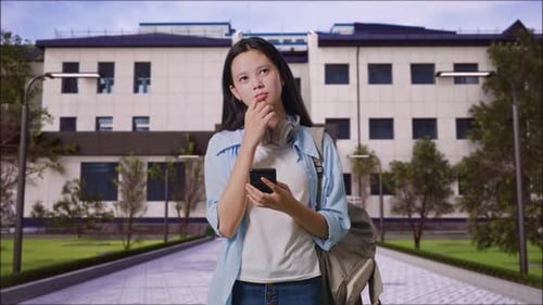 Girl Student Using A Smartphone And Thinking in Front of a School Building