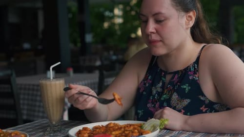 Cute Chubby Girl Eats Prawns in Tomato Sauce with Vegetables in Restaurant