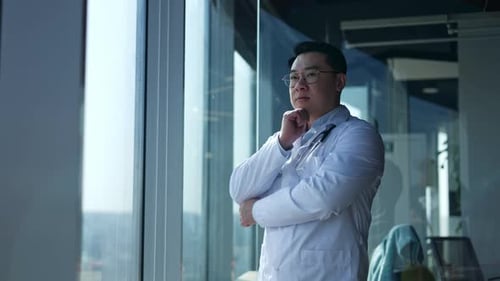 Physician Crossing Arms and Touching Chin While Thinking and Looking Out Window