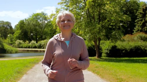 Senior Woman Jogging on Path in Green Park