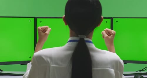 Happy Woman Celebrating While Working With Mock Up Multiple Monitor In Green Screen Studio