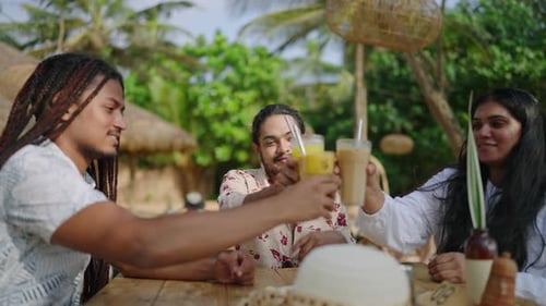 Amigos multiculturais desfrutam de bebidas em um café tropical. Grupo LGBT, brindes, sorrisos, saboreia bebidas