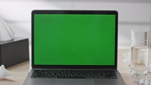 Modern Green Screen Laptop on Sick Person Desk Closeup Tissues and Water Glass