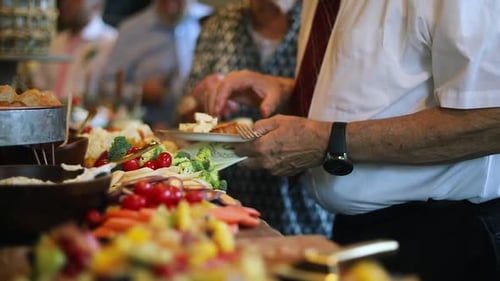 People Serving Themselves at Buffet Table with Food